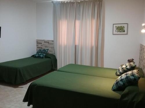 - une chambre avec 2 lits verts et une fenêtre dans l'établissement Hostal Residencia Cardona, à Arrecife