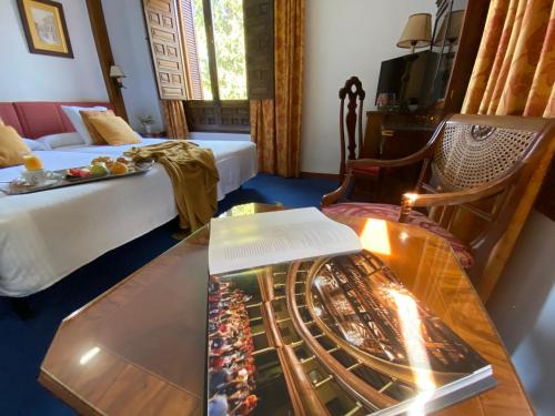 a room with a bed and a table with a book at Hotel El Bedel in Alcalá de Henares