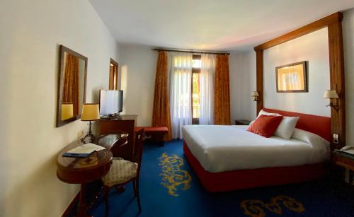 a hotel room with a bed and a desk and a bed sidx sidx at Hotel El Bedel in Alcalá de Henares