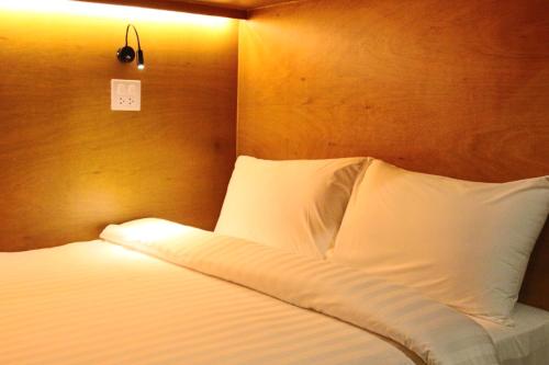 um quarto com uma cama com lençóis brancos e uma luz em GN Capsule Hostel Patong em Patong Beach