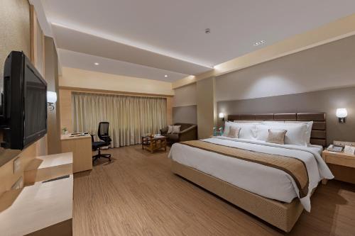 um quarto de hotel com uma cama grande e uma televisão em The Fern Residency Aurangabad - Chhatrapati Sambhaji Nagar em Aurangabad