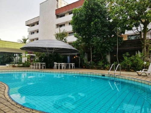 ein großer Pool mit Sonnenschirm, Tischen und Stühlen in der Unterkunft Terrace Hotel in Bandar Seri Begawan