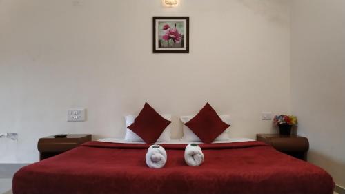 dos conejos blancos sentados en una cama roja en Bluebell Residency, en Mahabaleshwar