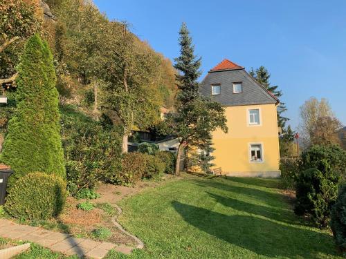 une maison jaune sur une colline avec une cour dans l'établissement Ferienhaus Elbufer 83, à Bad Schandau