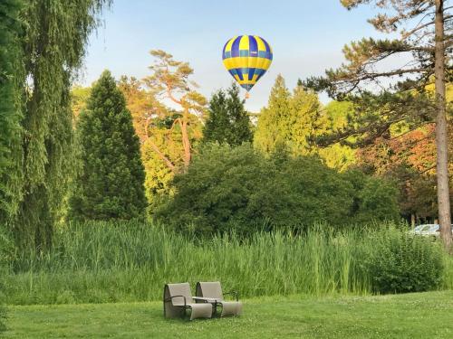 um balão de ar quente a voar sobre duas cadeiras num campo em Hostellerie De Levernois em Levernois