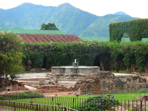 un jardin avec une fontaine et des montagnes en arrière-plan dans l'établissement Hotel Museo Spa Casa Santo Domingo, à Antigua Guatemala