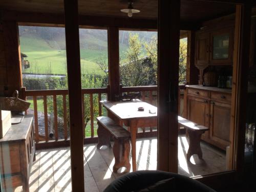 uma cozinha com uma mesa e uma varanda com vista em Chalet le 1791 em La Clusaz