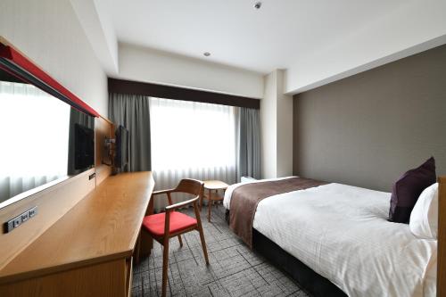 Habitación de hotel con cama, escritorio y TV. en Hotel Granvia Hiroshima, en Hiroshima