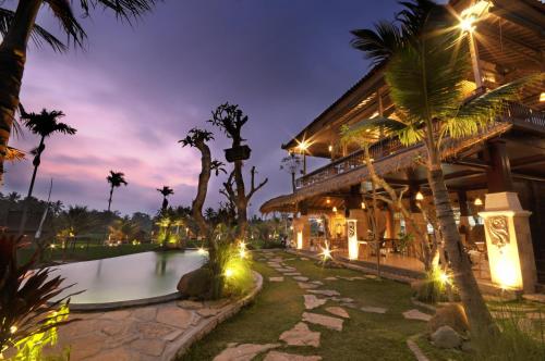 un complejo con piscina y palmeras por la noche en Pondok Sebatu Eco Lodge, en Tegalalang