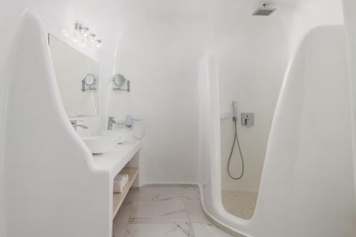 bagno bianco con lavandino e specchio di White Concept Caves - Adults Only a Firà