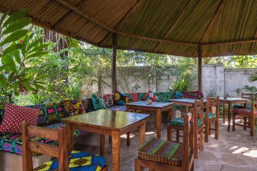 eine Terrasse mit Tischen und Stühlen unter einem Pavillon in der Unterkunft Muti Entebbe in Entebbe