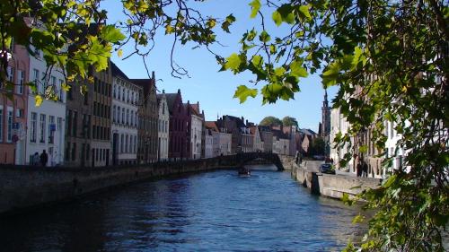 a river in a city with buildings and a bridge at Apartment Het Blekershuys in Bruges