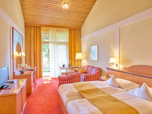 ein Hotelzimmer mit einem Bett und einem Wohnzimmer in der Unterkunft Parkhotel Bad Griesbach in Bad Griesbach