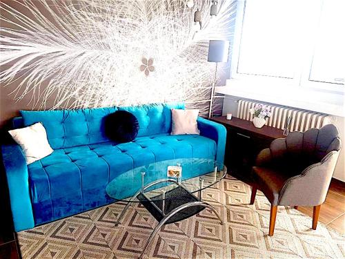 een blauwe bank in een woonkamer met een tafel bij Kristall Apartments 2 Panorama in Šabac