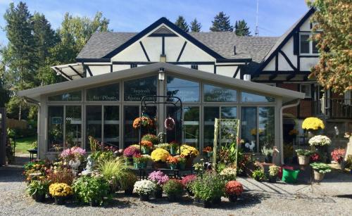 a greenhouse filled with flowers in front of a house at Burley's Executive Garden Suite in Peterborough