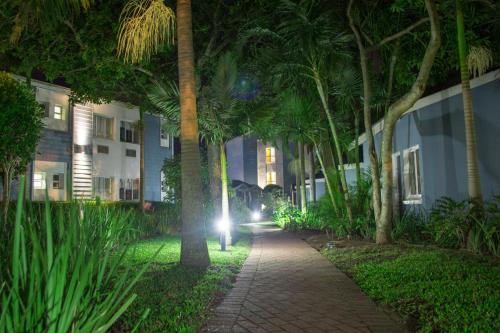 a walkway with palm trees in front of a building at Premier Splendid Inn Bayshore in Richards Bay