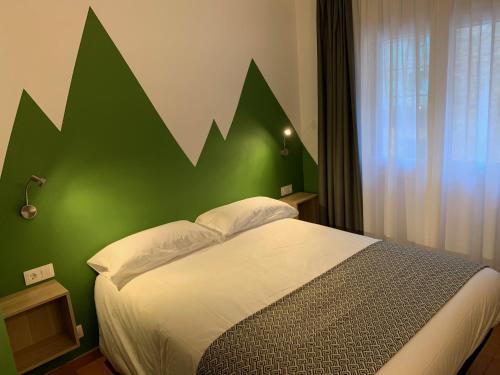 1 dormitorio con 1 cama con pared verde en Hotel Musher, en Pas de la Casa