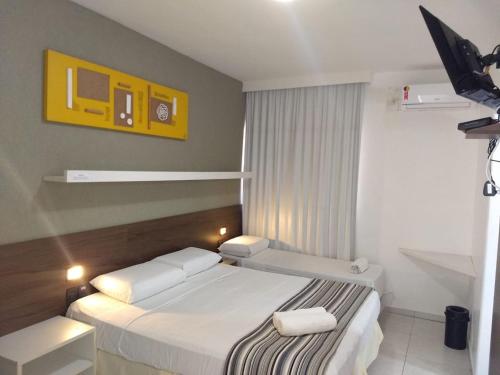 a bedroom with a white bed and a yellow picture at Pousada Aquarela Do Brasil in Maceió