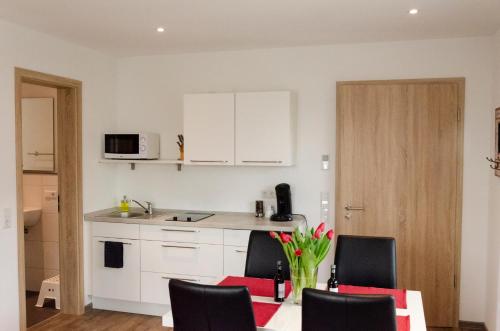 a kitchen with white cabinets and a table with chairs at LaVaTe in Kappel-Grafenhausen