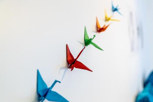 un grupo de aviones de origami volando en el cielo en B&B 1 uit de 100, en Gante