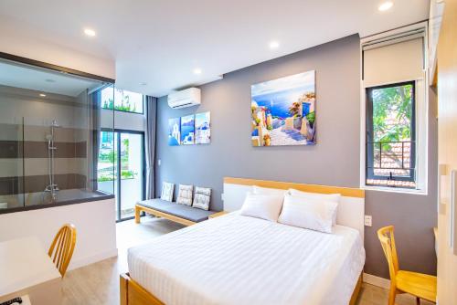 1 dormitorio con cama blanca, escritorio y silla en An Homestay, en Da Nang