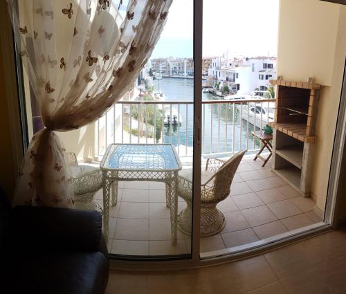 een kamer met een tafel en een balkon met uitzicht bij Magnífico apartamento junto al canal principal. in Empuriabrava