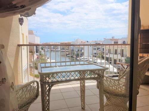 een balkon met een tafel en stoelen en uitzicht op een rivier bij Magnífico apartamento junto al canal principal. in Empuriabrava