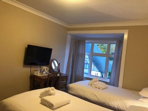 a hotel room with two beds and a window at Penny Farthing Hotel & Cottages in Lyndhurst