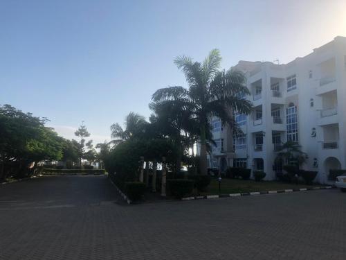 a street in front of a white building with palm trees at Almasi Oceanfront Nyali in Mombasa