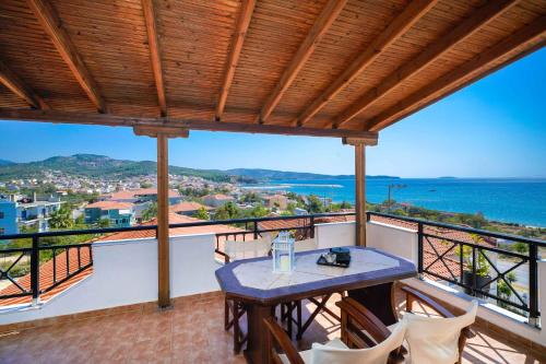 balcón con mesa, sillas y vistas al océano en Villa Golden Nest, en Limenaria