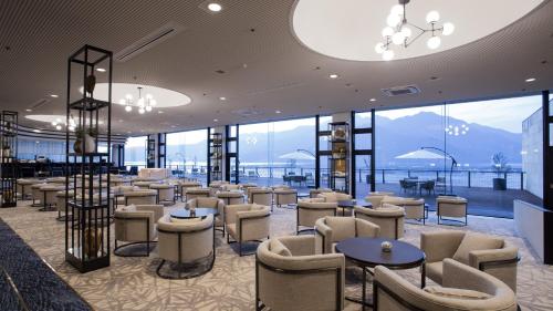 un restaurant avec des chaises, des tables et des fenêtres dans l'établissement Aki Grand Hotel & Spa, à Miyajima