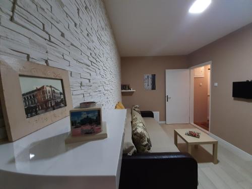 - un salon avec un canapé et un mur en pierre dans l'établissement Apartman Ana, à Šabac