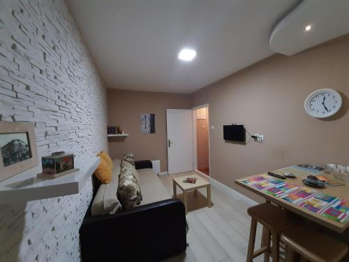 - un salon avec un canapé et un réveil sur le mur dans l'établissement Apartman Ana, à Šabac