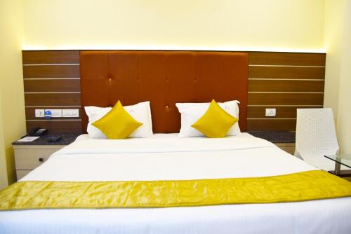 Un dormitorio con una cama grande con almohadas amarillas y blancas en Saibala Grand Airport Hotel, en Chennai