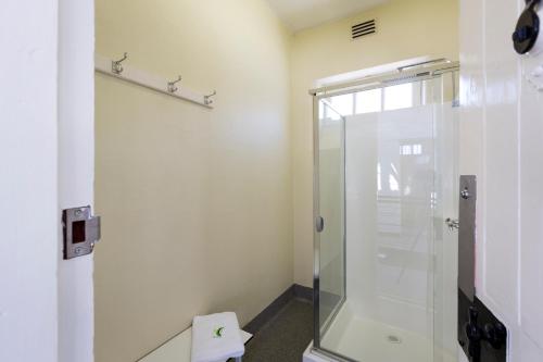 La salle de bains est pourvue d'une douche avec une porte en verre. dans l'établissement YHA Fremantle Prison, à Fremantle