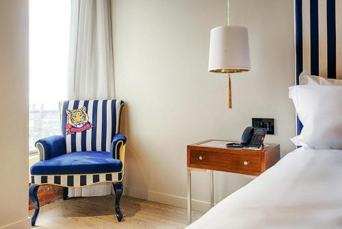 um quarto com uma cadeira azul e um telefone ao lado de uma cama em Monsieur Jean - Hôtel Particulier em Quebeque