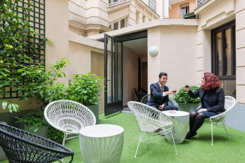 een man en vrouw op een patio met stoelen en tafels bij Hôtel Paris Vaugirard in Parijs