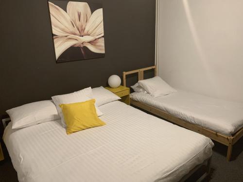 two beds with white sheets and a yellow pillow on them at Au Boeuf Rouge in Crassier