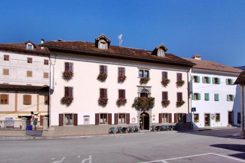 a large white building with plants on the windows at Albergo Alle Alpi in Comeglians