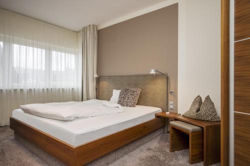 a bedroom with a bed and a table and a window at Hotel Am Helmwartsturm in Andernach