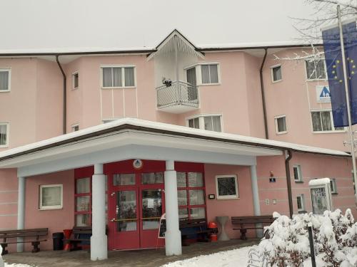 un edificio rosa con panchine di fronte di Jugend- und Familiengästehaus Klagenfurt a Klagenfurt