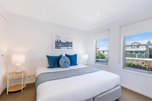 een witte slaapkamer met een groot bed en 2 ramen bij The Victoria Apartments in Port Fairy