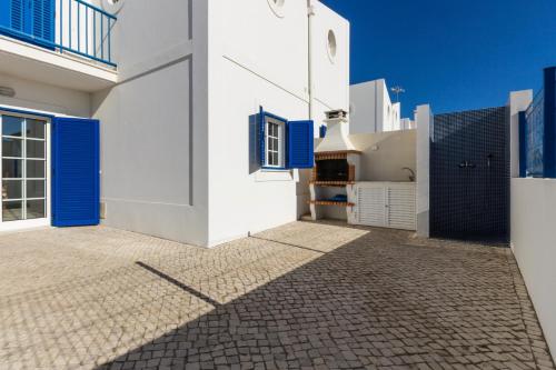 uma casa branca com portas azuis e um pátio em Blue Villa by ALGARVEMANTA na Manta Rota