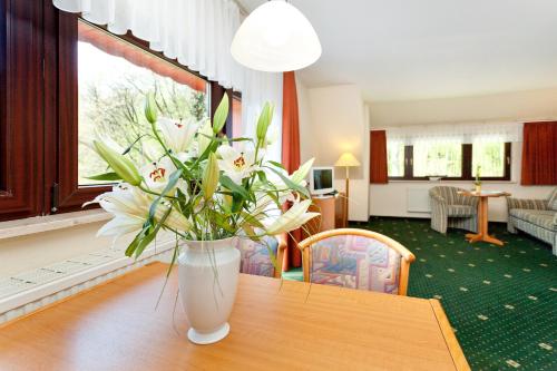 un jarrón con flores blancas sobre una mesa de madera en Restaurant & Hotel Baumhaus Hagen, en Sassnitz