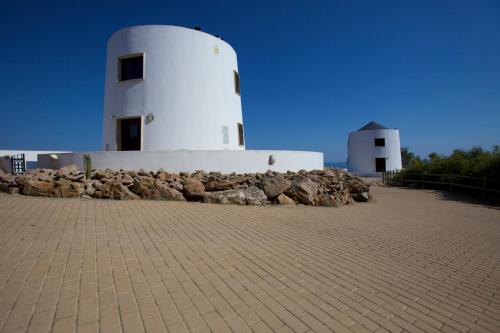 een witte vuurtoren met een berg stenen ernaast bij Quinta Dos Moinhos De Sao Filipe in Setúbal