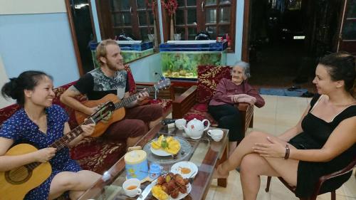 un gruppo di persone sedute in un soggiorno che suonano la chitarra di Halo Bay Homestay a Ha Long