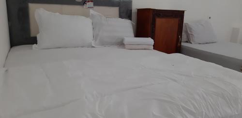 1 cama blanca grande con sábanas y almohadas blancas en Diyah Homestay, en Kuta Lombok