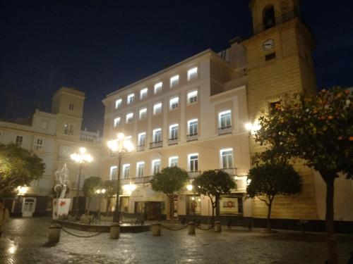 ein großes weißes Gebäude mit einem Uhrturm in der Nacht in der Unterkunft Hotel de Francia y París in Cádiz