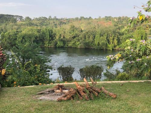 uma pilha de troncos sentados na relva ao lado de um rio em Nile it Resort em Jinja