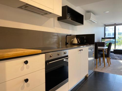 una cucina con armadi bianchi e forno nero di Midnight Luxe 1BR 1Bath Apartment 104 in the heart of Braddon Pool Sauna Secure Parking Wine WiFi a Canberra